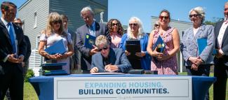 Governor McKee Signing a Bill next to a new housing development